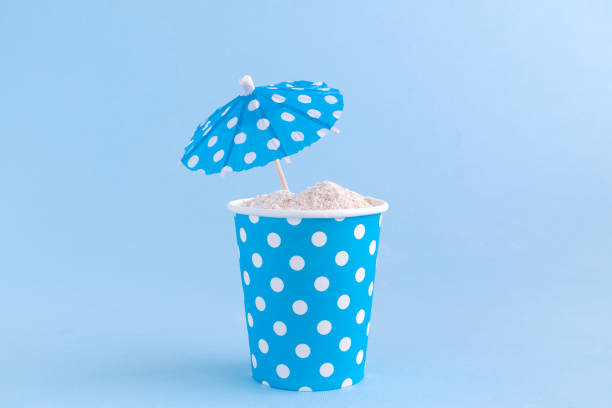 istock Paper cup full of sand and paper parasol. Sandy beach minimal creative concept. 931637634