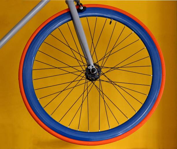 istock Carbon blue wheel with orange tyre, for  bicycle, on yellow background . 931645444