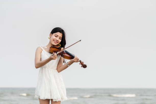 istock Happy woman playing violin on the beach. 931648918