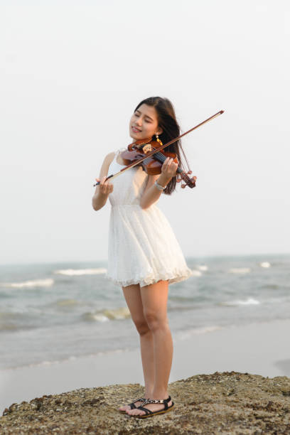 istock Happy woman playing violin on the beach. 931649016