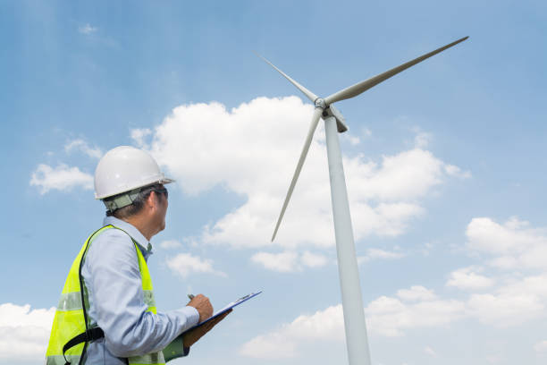 istock Electric Engineer writing report on Clipboard with Wind turbine power Generator 931650298