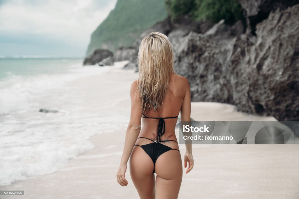 tätowierte Mädchen in schwarzen Badeanzug am Strand, jed mit dem Rücken zur Kamera posieren. Schöne blonde Frau mit langen Haaren Entspannung am Meer. Konzept der sportliche Modell Bademode - Lizenzfrei Frauen Stock-Foto