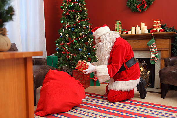 istock Santa Claus putting gifts under Christmas tree 93166469