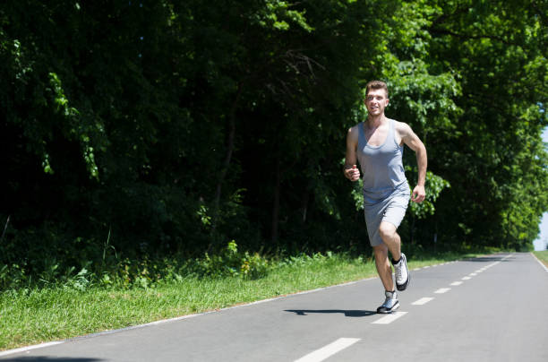 istock Young man jogging on treadmill in park, copy space 931666996