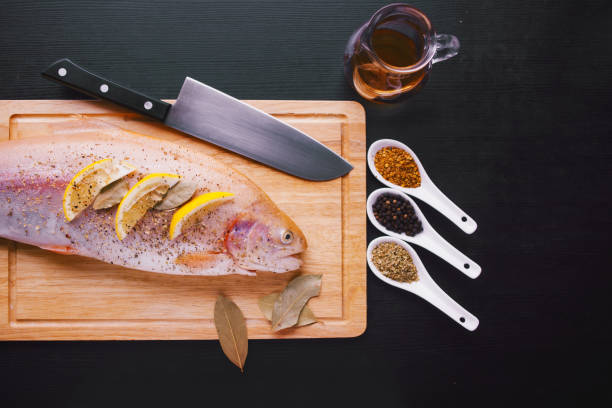 istock Fresh trout and ingredients to prepare fish dishes on black table 931667378