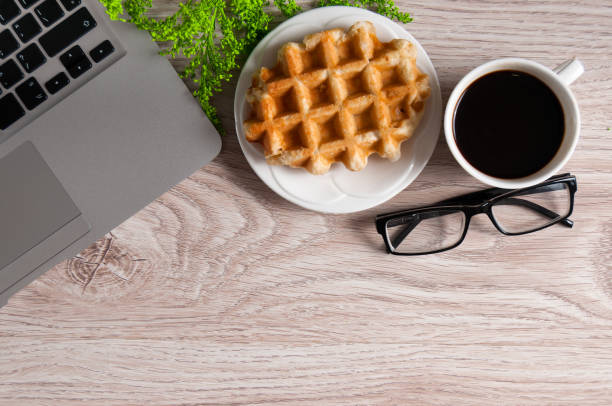 istock Notebook with hot coffee with wafer on wood table 931669958