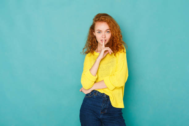 istock Secretive young woman placing finger on lips, hush sign 931669992
