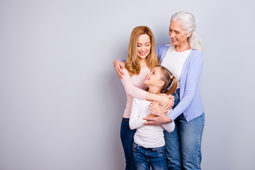 Family concept. Portrait of adorable lovely cute family generation standing hugging together wearing casual clothed isolated on gray background copyspace