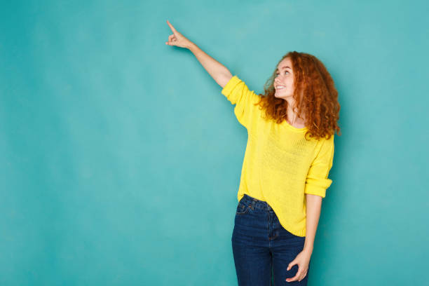 istock Excited redhead woman pointing up 931670050