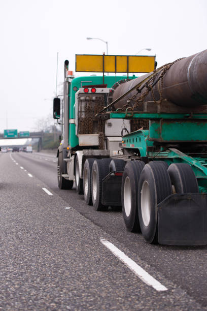 istock Big rig semi truck transporting oversize pipe cargo on the straight highway 931674902