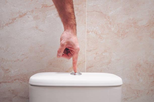 The hand presses the button on the toilet bowl, the economical drain The hand presses the button on the toilet bowl, the economical drain flushing toilet stock pictures, royalty-free photos & images