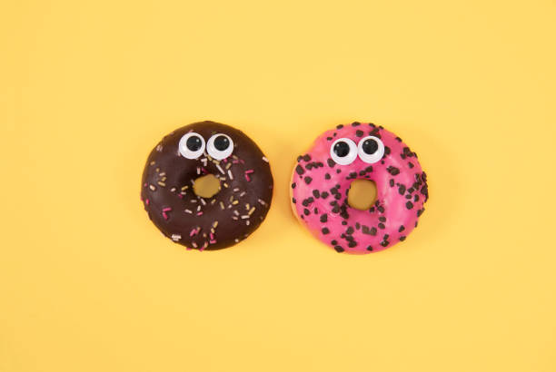 istock Colorful glazed donuts with funny eyes on yellow background 931687864