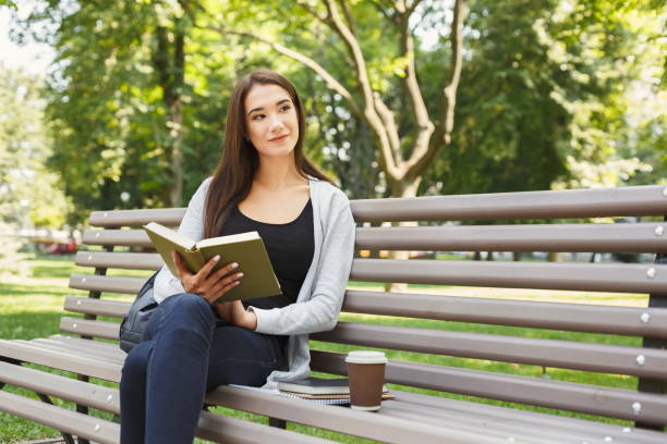 istock Young woman reading book in park copy space 931688590