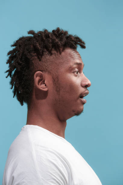 istock The surprised business Afro-American man standing and looking blue background. Profile view 931693834
