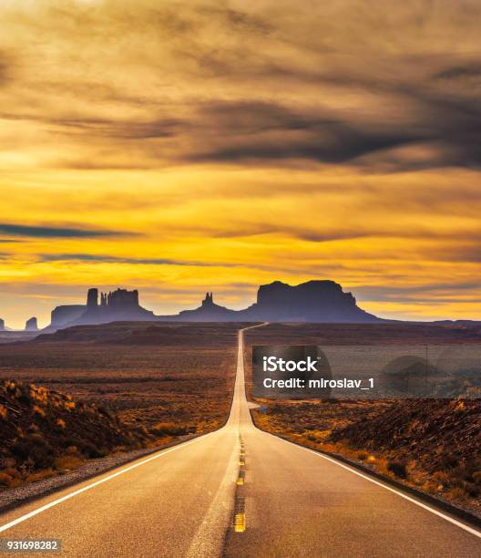 Desert Road Leading To Monument Valley At Sunset Stock Photo - Download Image Now - Sunset, Overcast, West - Direction