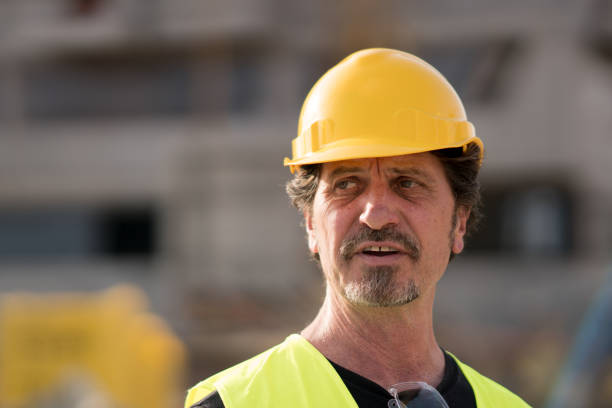 istock Civil engineer wearing yellow reflective vest and hardhat looking away 931701146