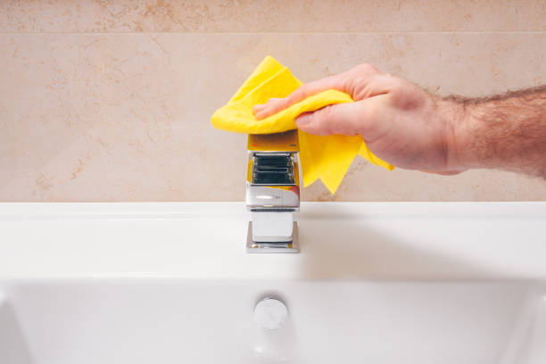 un hombre se lava y frota un nuevo hermoso grifo cromado en el baño - chromeplated fotografías e imágenes de stock