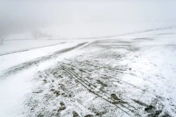 Footprints on snow-covered field on hillslope against foggy background - winter abstract