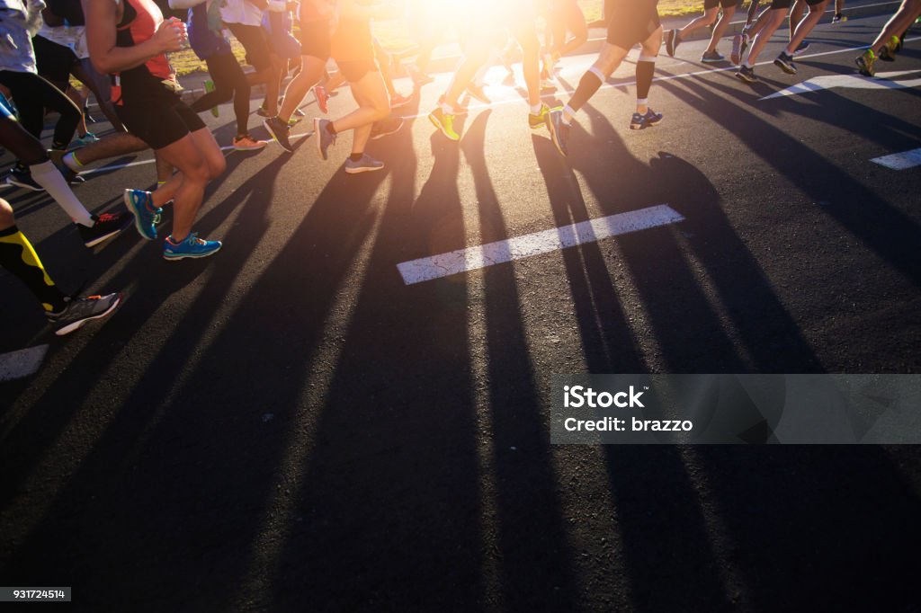 Shadows of joggers legs on the road Shadows of joggers legs on the road  at dawn Marathon Stock Photo