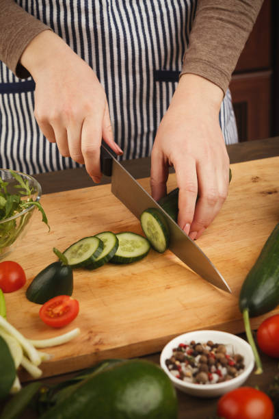 istock Woman cutting cucumber for fresh salad side view 931725662