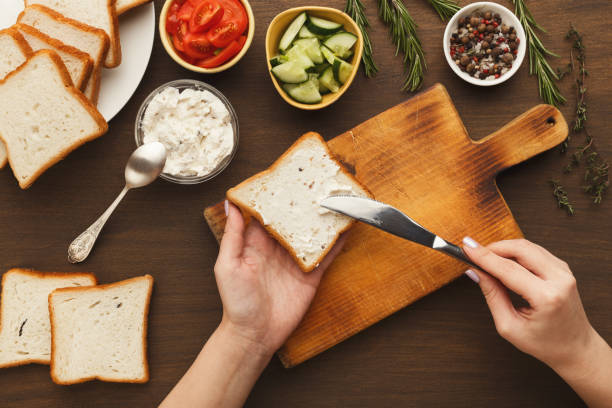 Woman cooking tasty sandwich, top view Woman cooking tasty sandwich with cream cheese, top view. Female hands spreading bruschetta topping on bread. Healthy eating concept making a sandwich stock pictures, royalty-free photos & images