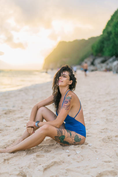 istock Woman sitting on the beach in Bali  at sunset 931744308