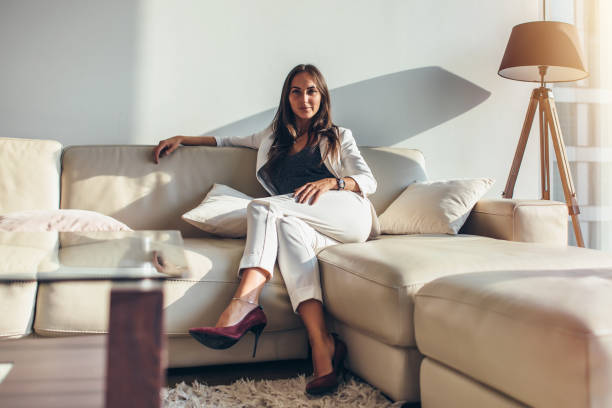 portrait de femme d’affaires assis sur le canapé détente après le travail à la maison - relaxation success luxury women photos et images de collection