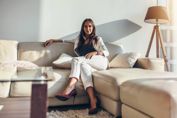 Portrait of businesswoman sitting on sofa relaxing after work at home Portrait of businesswoman sitting on sofa relaxing after work at home. wealthy lifestyle stock pictures, royalty-free photos & images
