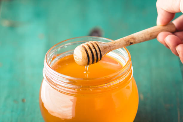 istock Honey in a glass bottle On blue wood in low light 931757922
