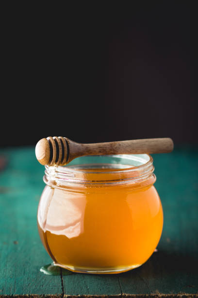 istock Honey in a glass bottle On blue wood in low light 931758098