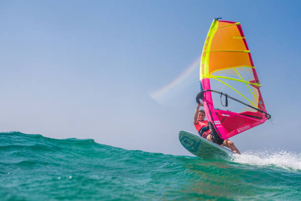 Windsurfing on sea Young woman windsurfing on sea with board and colourful sail. aquatic sport stock pictures, royalty-free photos & images