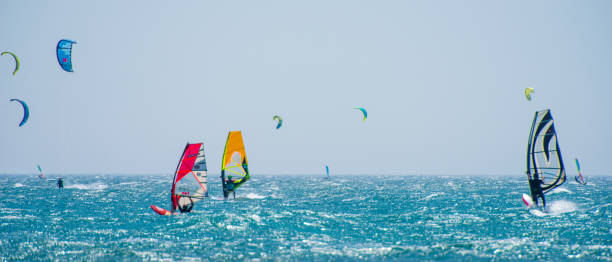People doing kitesurfing and windsurfing Group of people doing kitesurfing and windsurfing on sea. windsurfing stock pictures, royalty-free photos & images