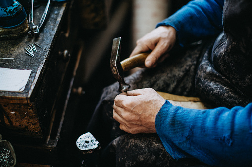 Shoemaker putting sole on shoe