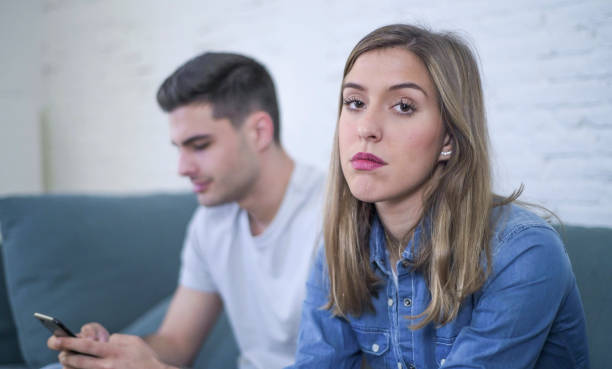 istock young attractive couple in relationship problem with internet mobile phone addiction boyfriend ignoring sad neglected and bored girlfriend at home couch feeling depressed and lonely 931768800