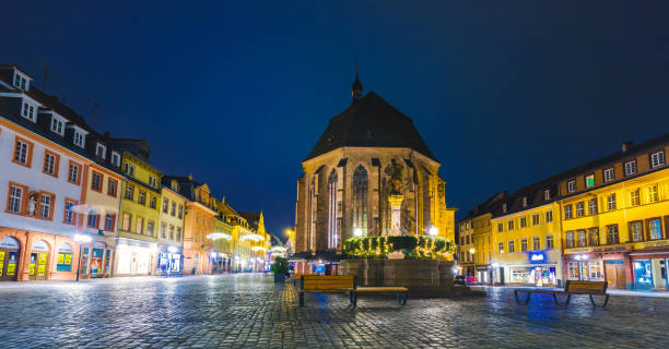 Heidelberg Shopping Street Scene with Old Holy Spirit Church at night in Germany Night scene of middle of the shopping market place and Church of the Holy Spirit on Marktplatz in Heidelberg, Baden-Wurttemberg, Germany. It is known as Heiliggeistkirche in German. heidelberg germany stock pictures, royalty-free photos & images