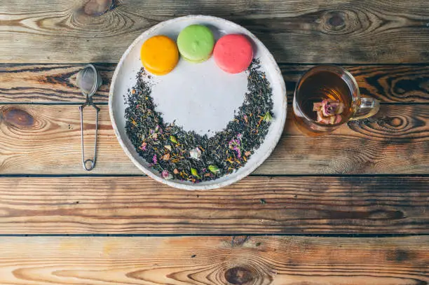 Tea with rose-petals and macaroon on a wooden table. Vintage composition