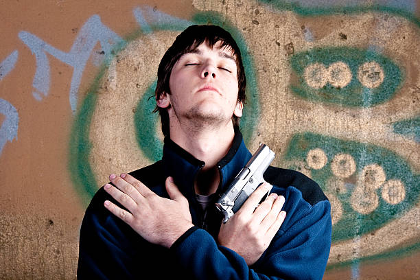 istock One young man with crossed arms holding a hand gun 93177275