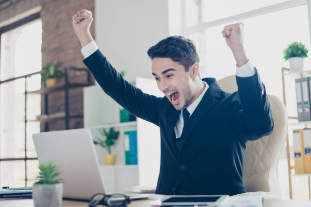Profile side view half-turned portrait of handsome crazy emotional delightful handsome yelling shouting with open mouth student raising hands in front of laptop sitting on armchair in workstation