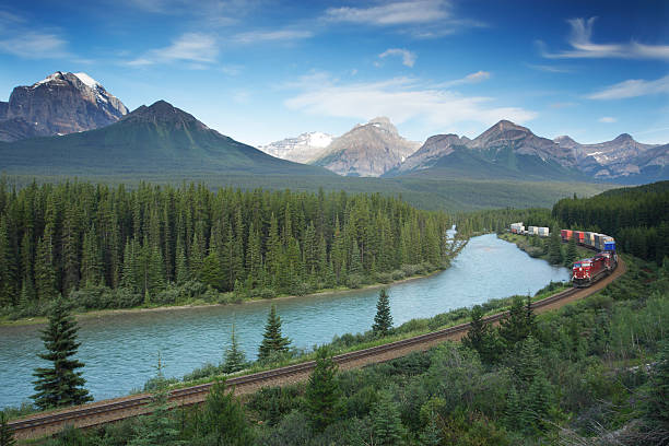 stazione ferroviaria con treno nel parco nazionale di banff, montagne rocciose canadesi - freight train foto e immagini stock