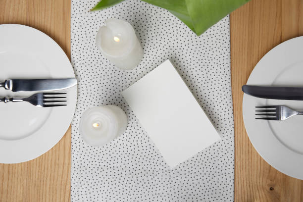 istock Dinnerware with cutlery on table next to blank card and candles 931793360