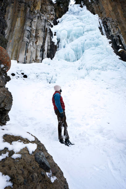 Man looks up at frozen Palisades Waterfall at Hyalite Canyon, Montana's most popular recreational area year round, Bozeman, MT, USA
