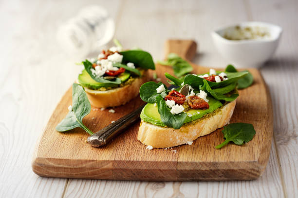 Healthy Spinach and avocado bruschetta Home made freshness home baked white bloomer with green pesto sauce,spinach,avocado bruschetta,service with feta fakes and pumpkpin seeds bruschetta stock pictures, royalty-free photos & images