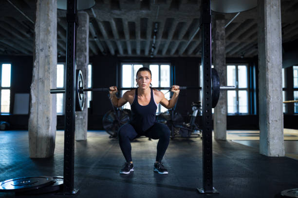 #value! - crouching exercising women barbell - fotografias e filmes do acervo