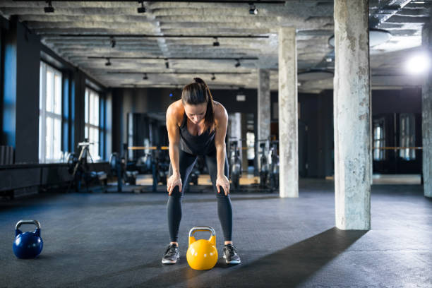 atleta stanco in piedi con le mani sulle ginocchia in palestra - kettle bell sport women muscular build foto e immagini stock