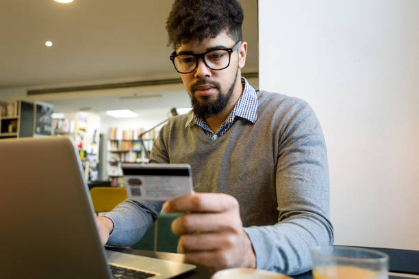 istock Young man at the library making credit card purchase online using laptop 931805196