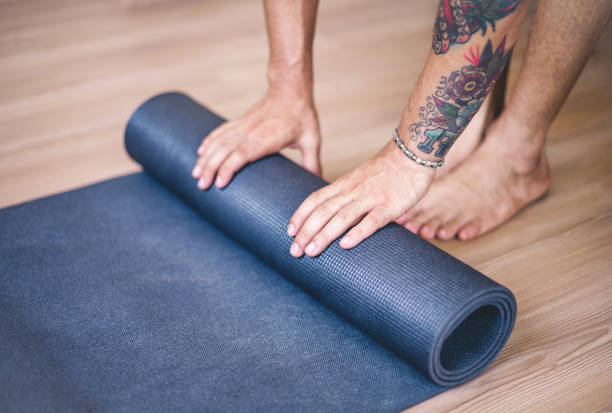 Yoga training concept Close up young yogi men rolling mat man yoga tattoo stock pictures, royalty-free photos & images