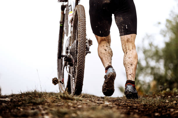 ciclista atleta posteriore con salita in mountain bike sporca in salita - at the foot of the cross foto e immagini stock