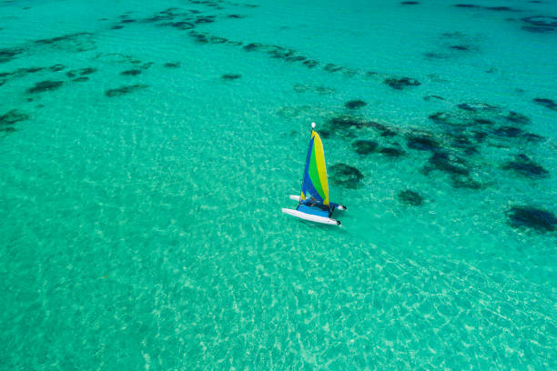 vista aérea drone de vela surf velero o catamarán en aguas de color turquesa del mar caribe cerca de la playa de punta cana. - hawaii islands summer surfboard tropical climate fotografías e imágenes de stock