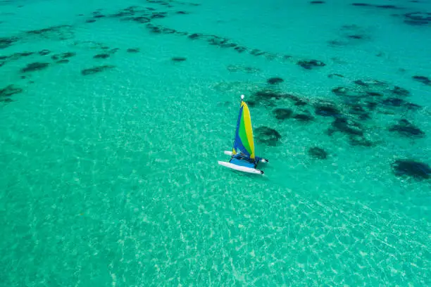 Aerial drone view of sailing sailboat surf or catamaran in turquoise water of Caribbean sea near Punta Cana beach.