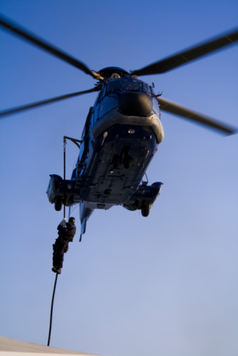 Special forces (SWAT) member descending on rope from a helicopter (a French made AS 332 L1 Super Puma Euro Copter)